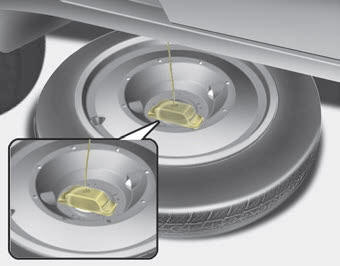 Kia Carnival: Storing the spare tire. 1. Assemble the cover and spare tire with valve center aligning together.